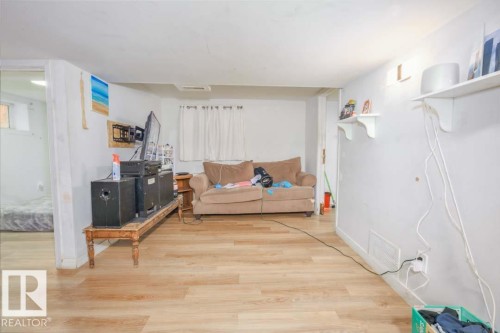 Light wood-finish flooring throughout, white painted walls, and built-in wall shelving - 11308 94 Street, Edmonton, AB 
