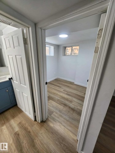 Room featuring wood-finish flooring, two small windows, and a recessed ceiling light - 11308 94 Street, Edmonton, AB 