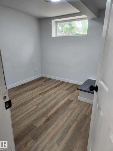 Room featuring wood-finish flooring, white baseboards, and light gray walls - 11308 94 Street, Edmonton, AB 