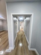 Hallway featuring wood-finish flooring, light grey wall paint, white trim, and recessed lighting - 