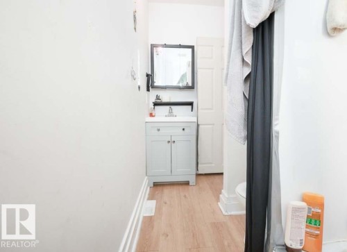 Bathroom featuring a light-colored vanity with a white countertop and a rectangular mirror with a dark frame - 11308 94 Street, Edmonton, AB 