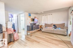Open-concept room featuring wood-finish flooring, white walls, and a window with white curtains - 