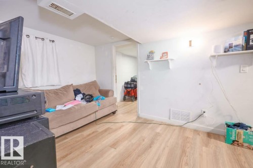 Room featuring wood-finish flooring, white painted walls, and an overhead air vent - 11308 94 Street, Edmonton, AB 
