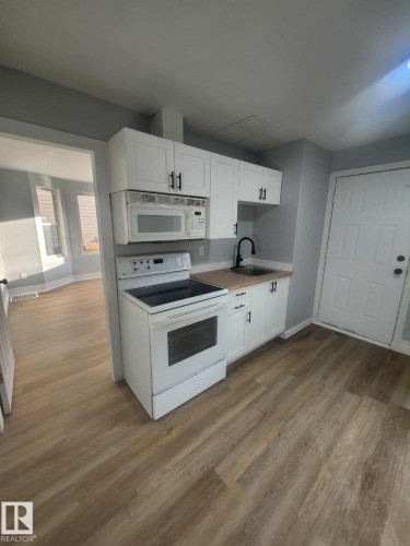 Kitchen featuring white cabinetry, wood-finish countertops, and a black gooseneck faucet - 11308 94 Street, Edmonton, AB 