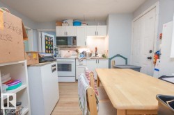 Kitchen featuring white cabinetry, light countertops, wood-finish flooring, and a built-in microwave - 