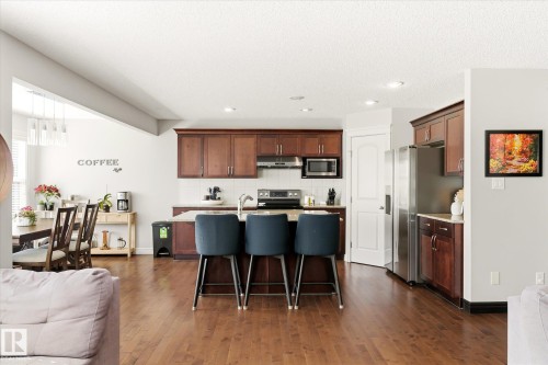 Kitchen island featuring seating for three, complemented by stainless steel appliances and wood-finish cabinetry - 3685 Westcliff Way, Edmonton, AB 