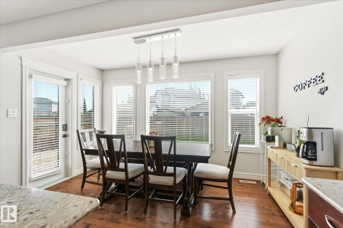 Bright dining area featuring rich wood-finish flooring and a contemporary linear pendant light fixture - 3685 Westcliff Way, Edmonton, AB 