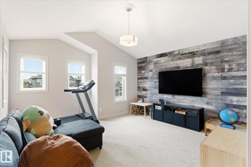 Spacious room featuring a vaulted ceiling and a decorative accent wall with wood-finish paneling - 3685 Westcliff Way, Edmonton, AB 