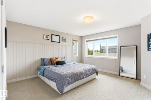 Bedroom featuring a large window, light-colored carpet flooring, a ceiling-mounted light fixture, and vertical paneling on one wall - 3685 Westcliff Way, Edmonton, AB 