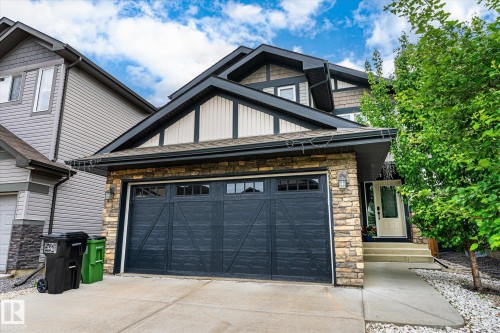 Exterior featuring stone veneer accents, multi-pane garage door, and a covered entry - 3685 Westcliff Way, Edmonton, AB 