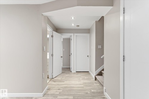 Hallway featuring wood-finish flooring, recessed lighting, neutral wall paint, white trim, and white interior doors - 3685 Westcliff Way, Edmonton, AB 