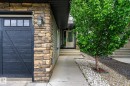 Stone veneer accents complementing grey siding with a dark carriage-style garage door - 3685 Westcliff Way, Edmonton, AB 