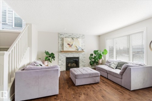 Spacious living area featuring wood-finish flooring and a white railing staircase - 3685 Westcliff Way, Edmonton, AB 