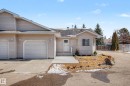 Residence featuring light beige siding, an attached single-car garage, a paved driveway, and a concrete walkway leading to the entry - 21 1850 Mill Woods Road E, Edmonton, AB 
