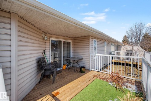 Covered wood-finish deck with white railings and vinyl siding - 21 1850 Mill Woods Road E, Edmonton, AB 