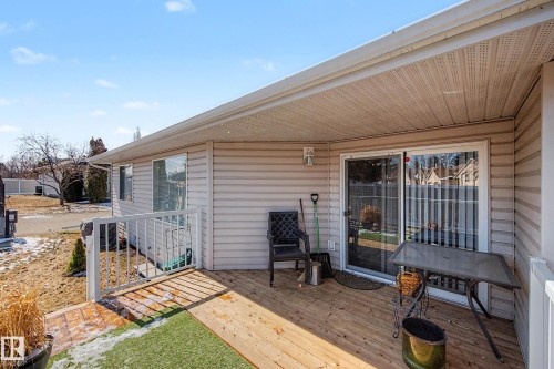 Rear patio featuring wood decking and a white railing - 21 1850 Mill Woods Road E, Edmonton, AB 