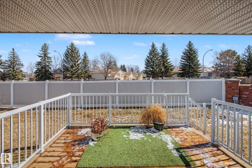 Covered patio with durable vinyl soffit, white railing, and a composite deck surface - 21 1850 Mill Woods Road E, Edmonton, AB 