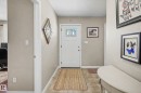Entryway featuring a white paneled door with decorative glass inserts, neutral wall color, and tile flooring - 21 1850 Mill Woods Road E, Edmonton, AB 