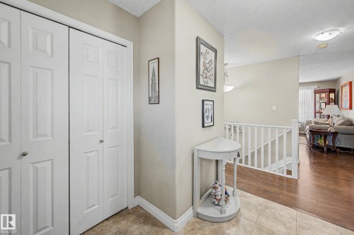 Foyer featuring tile flooring, white bi-fold closet doors, and light neutral wall paint - 21 1850 Mill Woods Road E, Edmonton, AB 