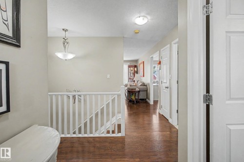 Hallway with wood-finish flooring, light neutral wall paint, and white trim - 21 1850 Mill Woods Road E, Edmonton, AB 