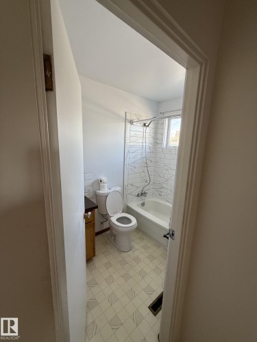 Full bathroom featuring a white bathtub, ceramic tile surround, and a coordinating toilet - 16321 - 109A Ave, Edmonton, AB - Indoor Photo Showing Bathroom