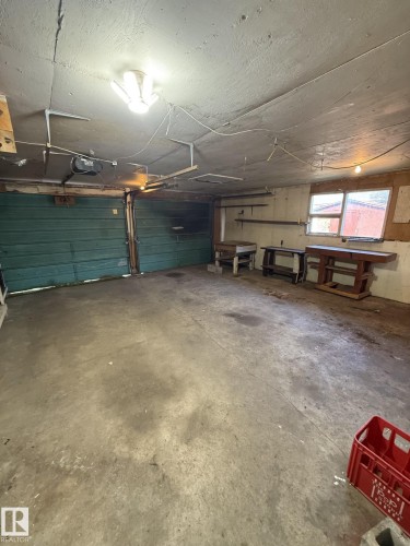 Two vehicle garage featuring concrete flooring and dual green roll-up doors - 16321 - 109A Ave, Edmonton, AB - Indoor Photo Showing Garage