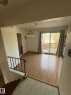 Open-plan living space featuring wood-finish flooring, a contemporary chandelier, and direct access to an outdoor deck through a sliding glass door - 16321 - 109A Ave, Edmonton, AB  - Indoor Photo Showing Other Room 