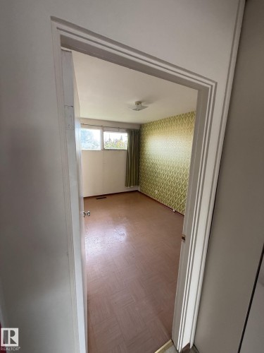 Room featuring patterned wallpaper, parquet flooring, a window with vertical blinds, and a flush mount ceiling light - 16321 - 109A Ave, Edmonton, AB - Indoor Photo Showing Other Room