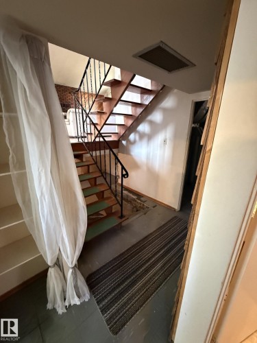 Interior staircase featuring open risers, wrought iron balusters, and exposed brickwork in the background - 16321 - 109A Ave, Edmonton, AB - Indoor Photo Showing Other Room