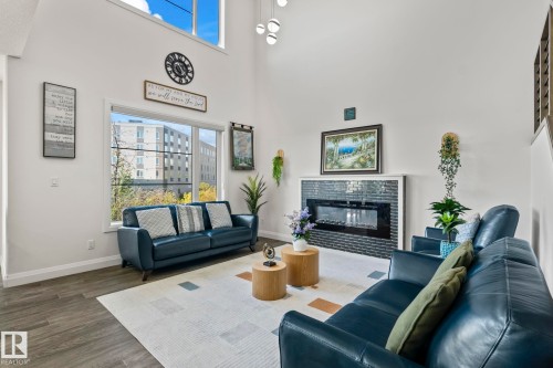 Vaulted ceilings elevate this living space, featuring large picture windows and wood-finish flooring - 23 Elwyck Gate, Spruce Grove, AB 