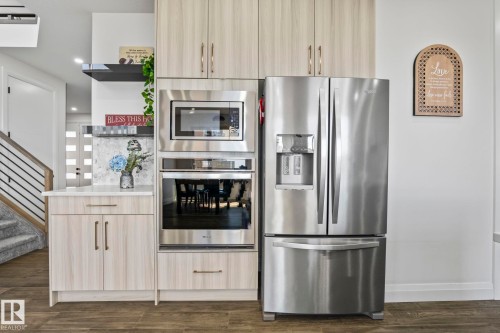 Integrated stainless steel appliances featuring a French door refrigerator and a built-in oven with microwave - 23 Elwyck Gate, Spruce Grove, AB 