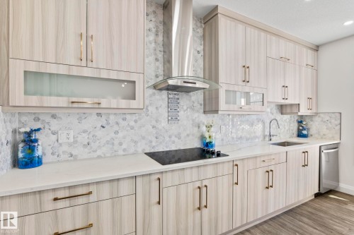 Modern kitchen featuring light wood-finish cabinetry with contemporary hardware, a mosaic tile backsplash, and white countertops - 23 Elwyck Gate, Spruce Grove, AB 