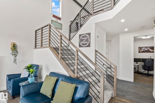 Two-story entry with high ceilings, contemporary staircase featuring wood-finish railings and black metal balusters, carpeted treads, and recessed lighting - 23 Elwyck Gate, Spruce Grove, AB 