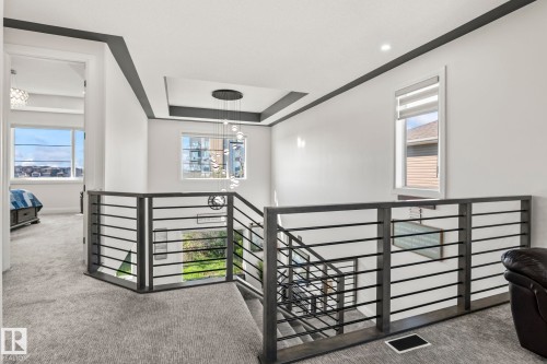 Upper-level landing featuring contemporary metal railings, recessed lighting, and a modern chandelier - 23 Elwyck Gate, Spruce Grove, AB 