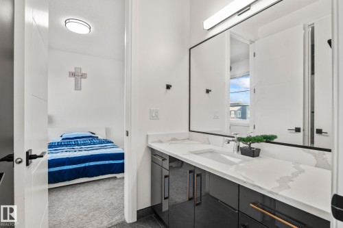 Bathroom vanity featuring a single undermount sink, a white countertop with grey veining, and dark cabinetry with gold-toned hardware - 23 Elwyck Gate, Spruce Grove, AB 