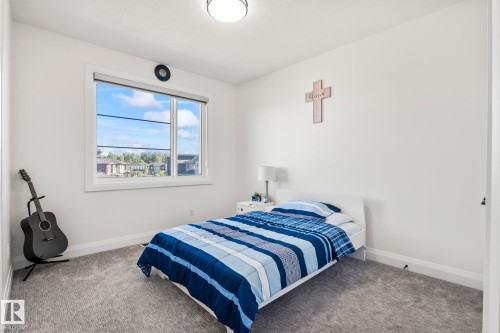 Bright room with a large window, plush gray carpeting, white walls, and a contemporary ceiling light fixture - 23 Elwyck Gate, Spruce Grove, AB 