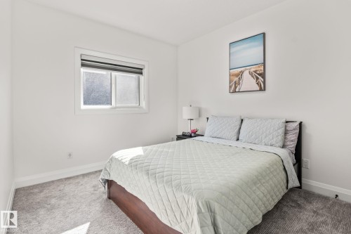 Neutral wall color, window with roller shade, gray carpeting, white trim, and a dark wood-finish bed frame - 23 Elwyck Gate, Spruce Grove, AB 