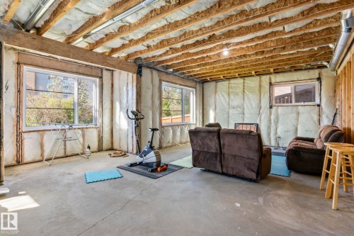 Unfinished basement space featuring exposed wood joists and structural beams, multiple windows, batt insulation, and a concrete floor - 23 Elwyck Gate, Spruce Grove, AB 