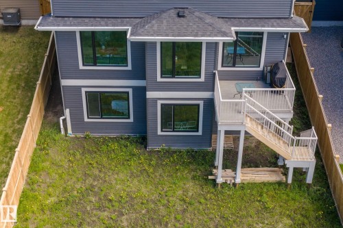 Rear exterior featuring gray siding, a multi-level deck with white railings, and a staircase descending to the backyard - 23 Elwyck Gate, Spruce Grove, AB 