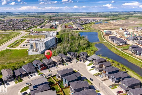 Aerial perspective showcasing a residential neighborhood with modern homes, multiple retention ponds, and a paved walking path - 23 Elwyck Gate, Spruce Grove, AB 