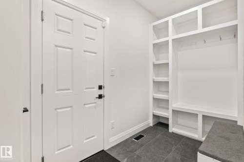 Entryway mudroom featuring built-in white shelving, integrated bench seating, and durable dark tile flooring - 23 Elwyck Gate, Spruce Grove, AB 