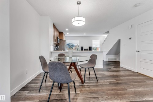 Open-concept dining area featuring wood-finish flooring, a contemporary ceiling light fixture, and white baseboards - 116 3305 Orchards Link Sw, Edmonton, AB 