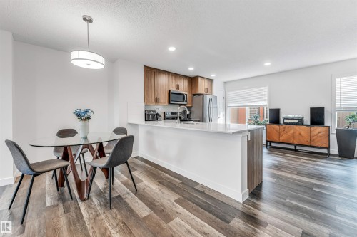 Open-concept living space featuring wood-finish flooring throughout - 116 3305 Orchards Link Sw, Edmonton, AB 