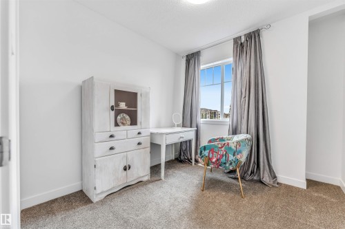 Bright room featuring neutral carpeting, a large window with white framing, and white painted walls - 116 3305 Orchards Link Sw, Edmonton, AB 