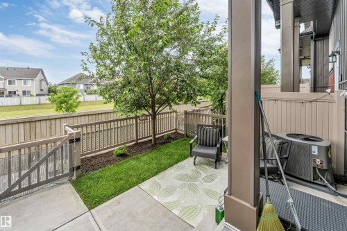 Paved patio area featuring concrete flooring, a small lawn, and a mature tree - 116 3305 Orchards Link Sw, Edmonton, AB 