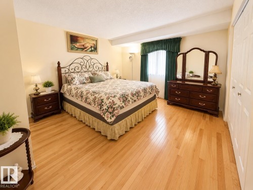 Bedroom featuring wood-finish flooring, a window with drapery, and a bifold closet door - 1 Munro Court, Leduc, AB 