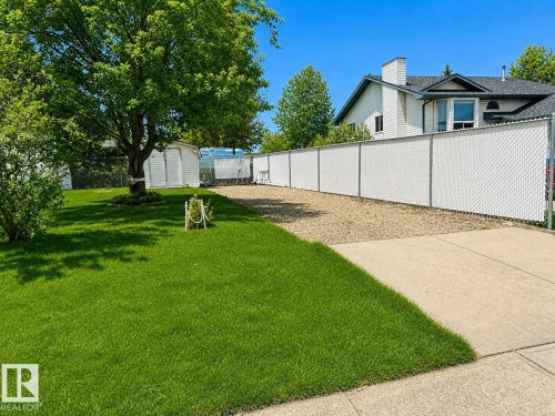 White chain-link fence with privacy slats bordering a gravel area - 1 Munro Court, Leduc, AB 