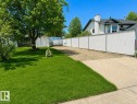 White chain-link fence with privacy slats bordering a gravel area - 1 Munro Court, Leduc, AB 