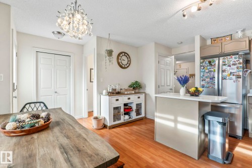 Dining area featuring a contemporary chandelier, wood-finish flooring, and white double-panel doors - 220 85St, Edmonton, AB 