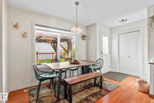 Dining area featuring wood-finish flooring, a large window, and a crystal chandelier - 220 85St, Edmonton, AB 
